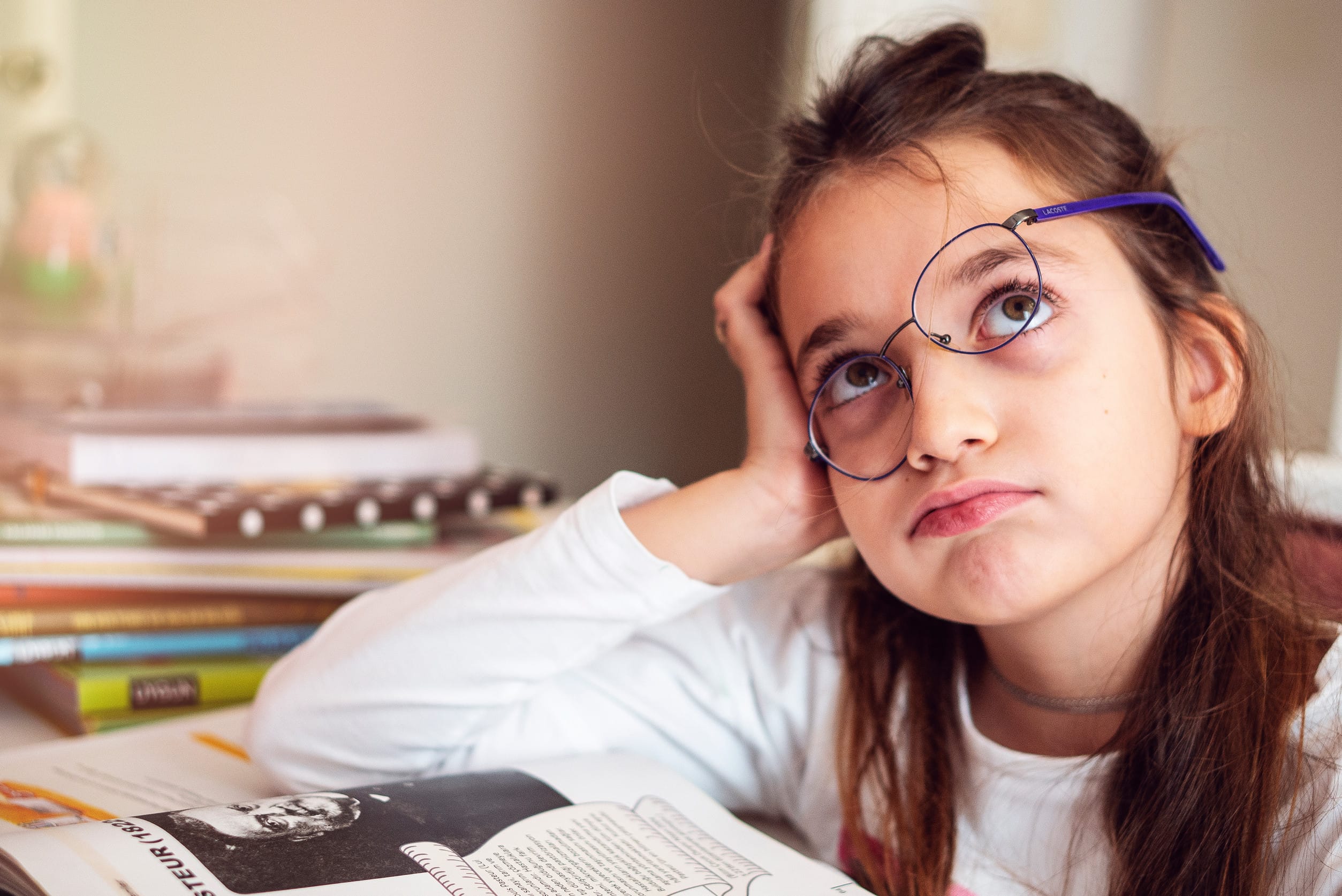 Bored little girl at home. Cute child doing homework. Modern education, communication