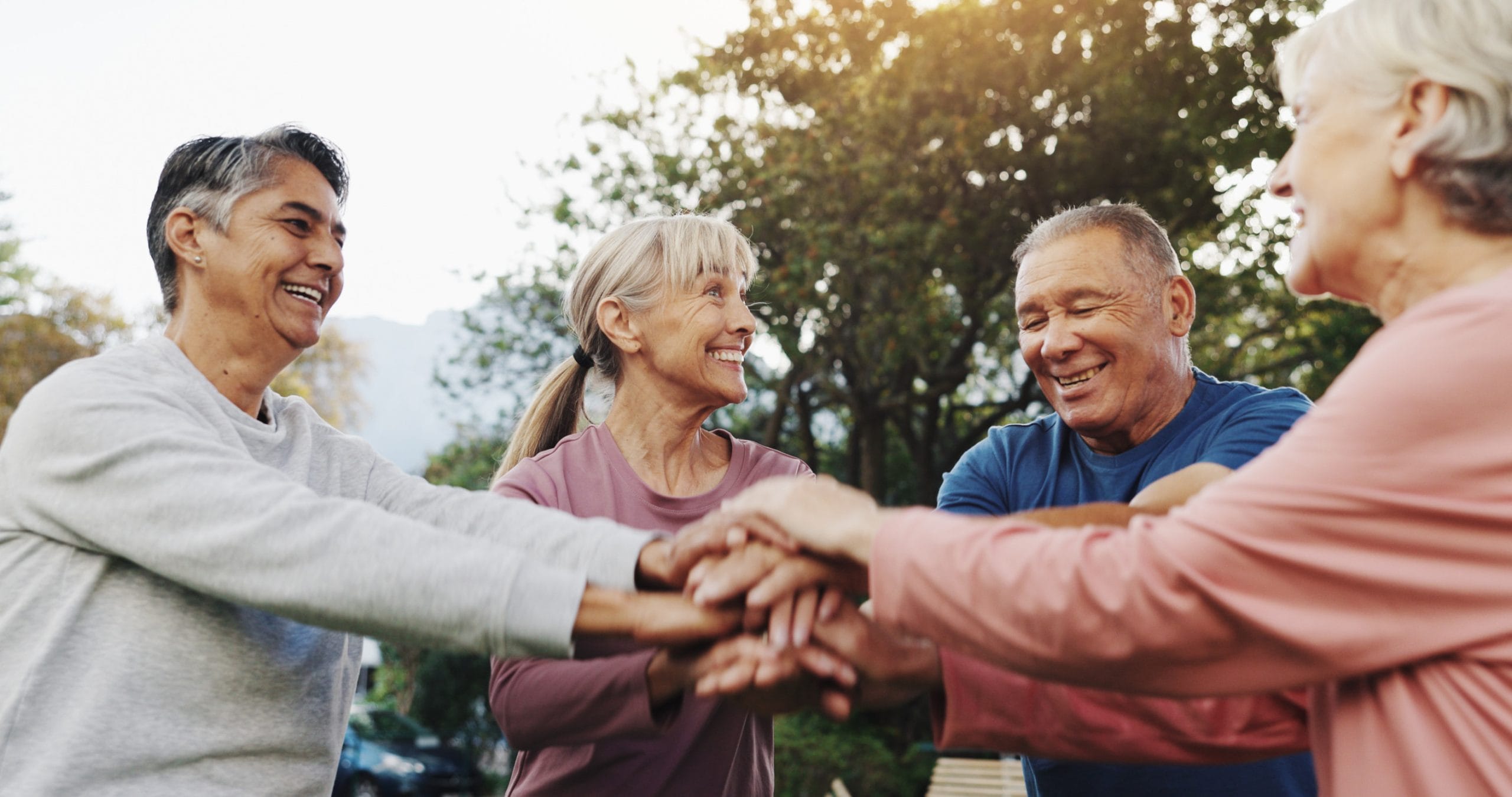 Nature, senior people and hands with huddle for fitness, support and celebration together with smile. Outdoor, retirement and friends with stack for solidarity, exercise goal or happy with motivation.