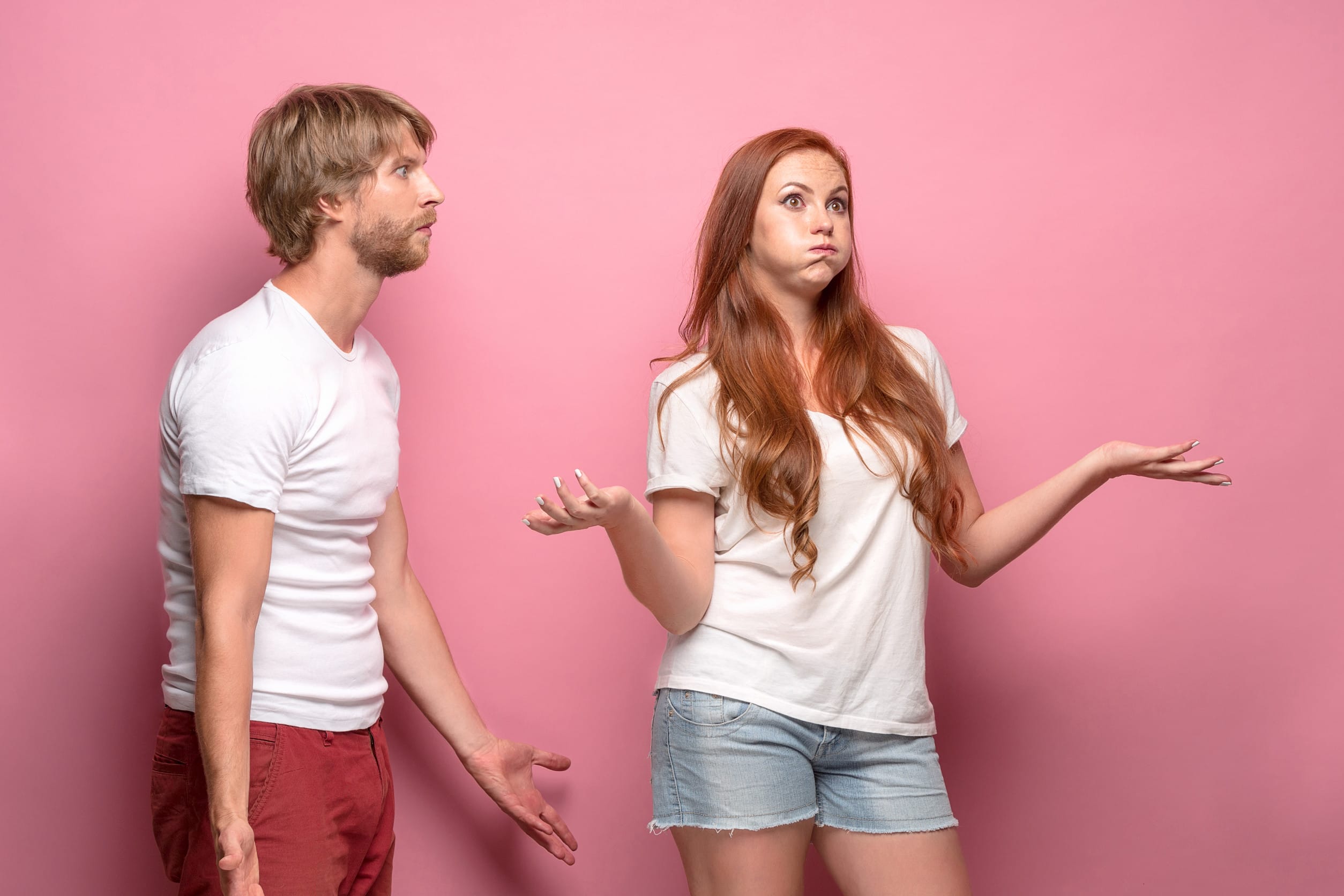 The conflict of couple - woman threatening and showing strength on pink background
