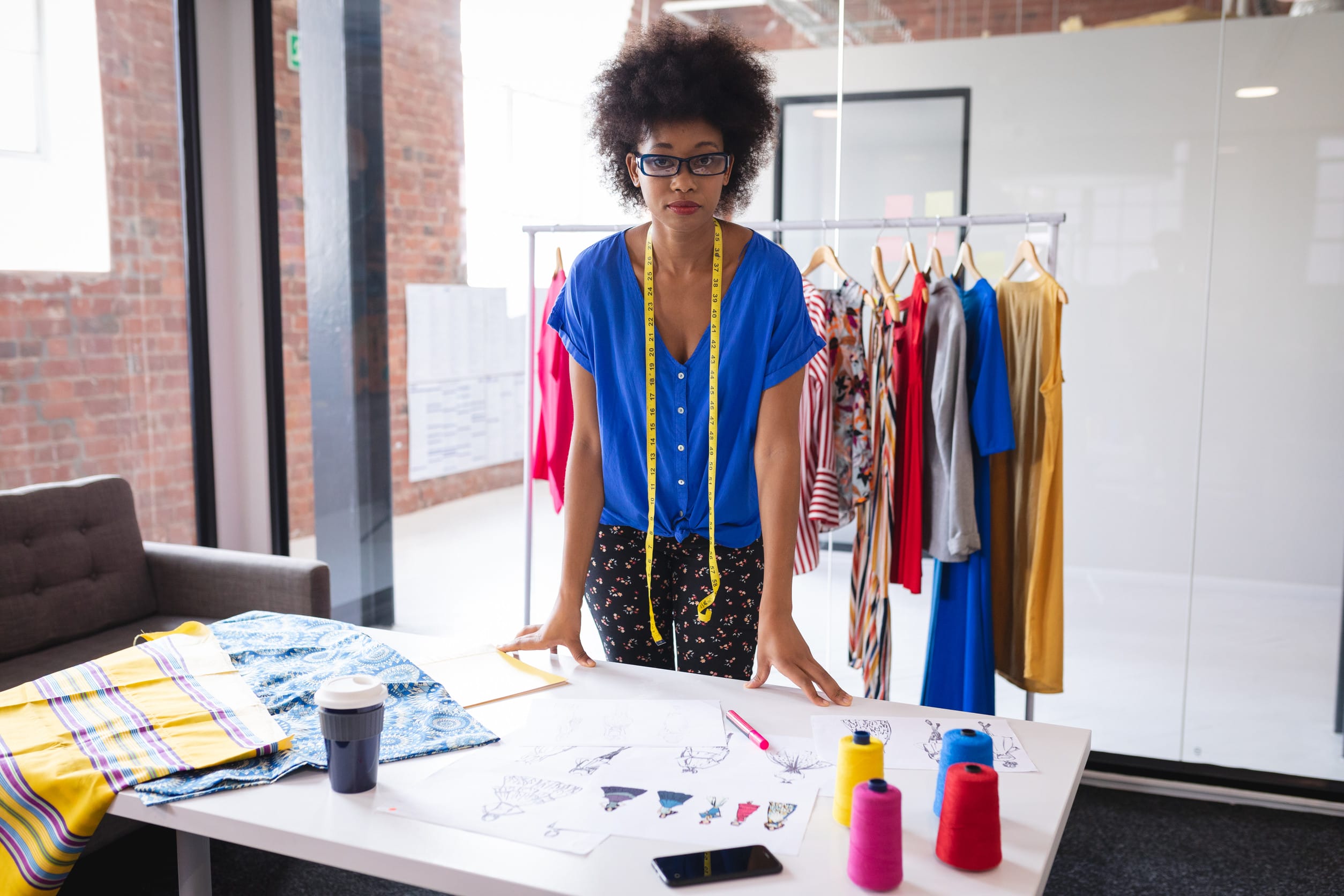 Mixed race fashion designer working in office with fabrics and sketches on the table. independent creative design business.