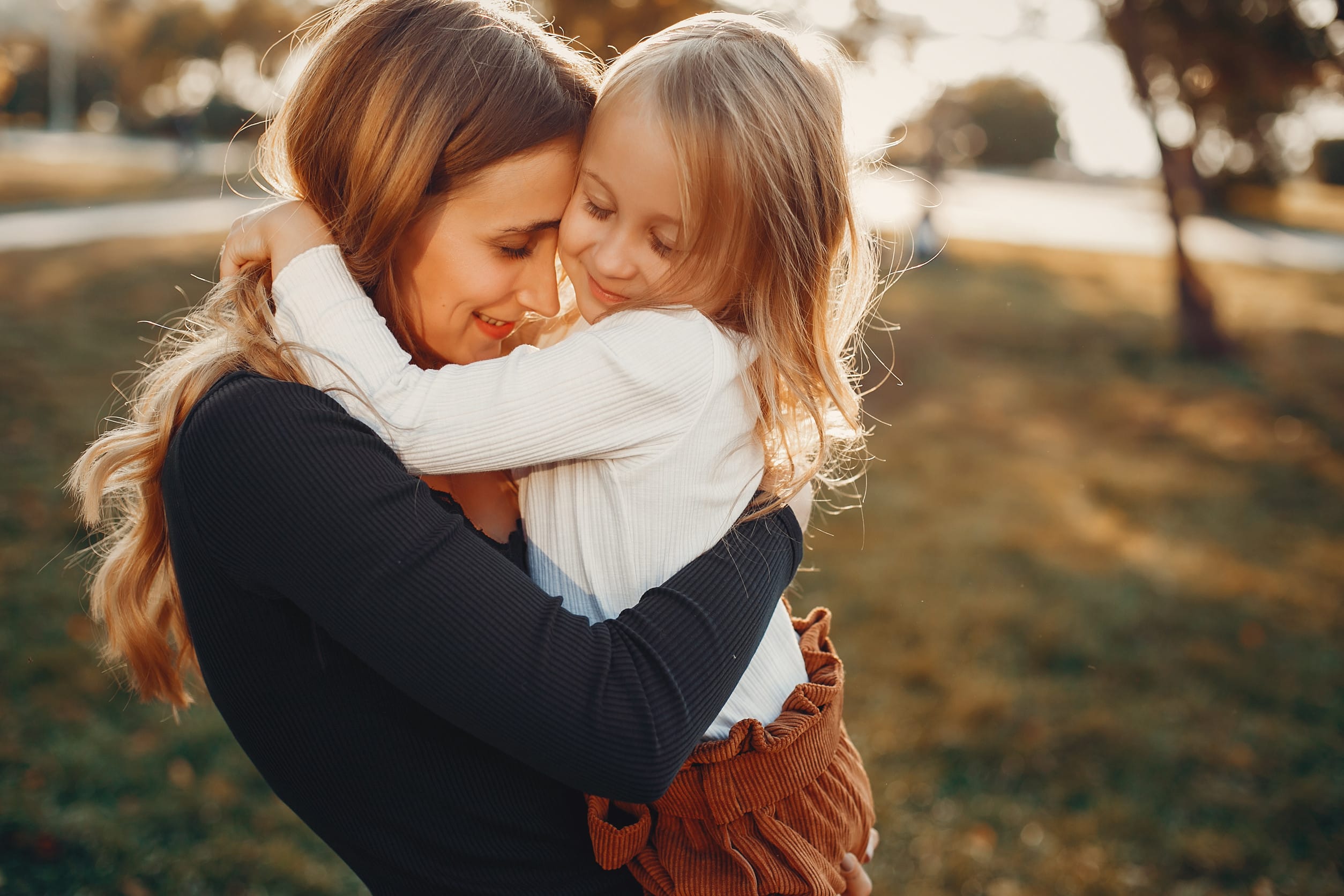 Stylish mother with cute little daughter in a park. Little girl with blonde hair