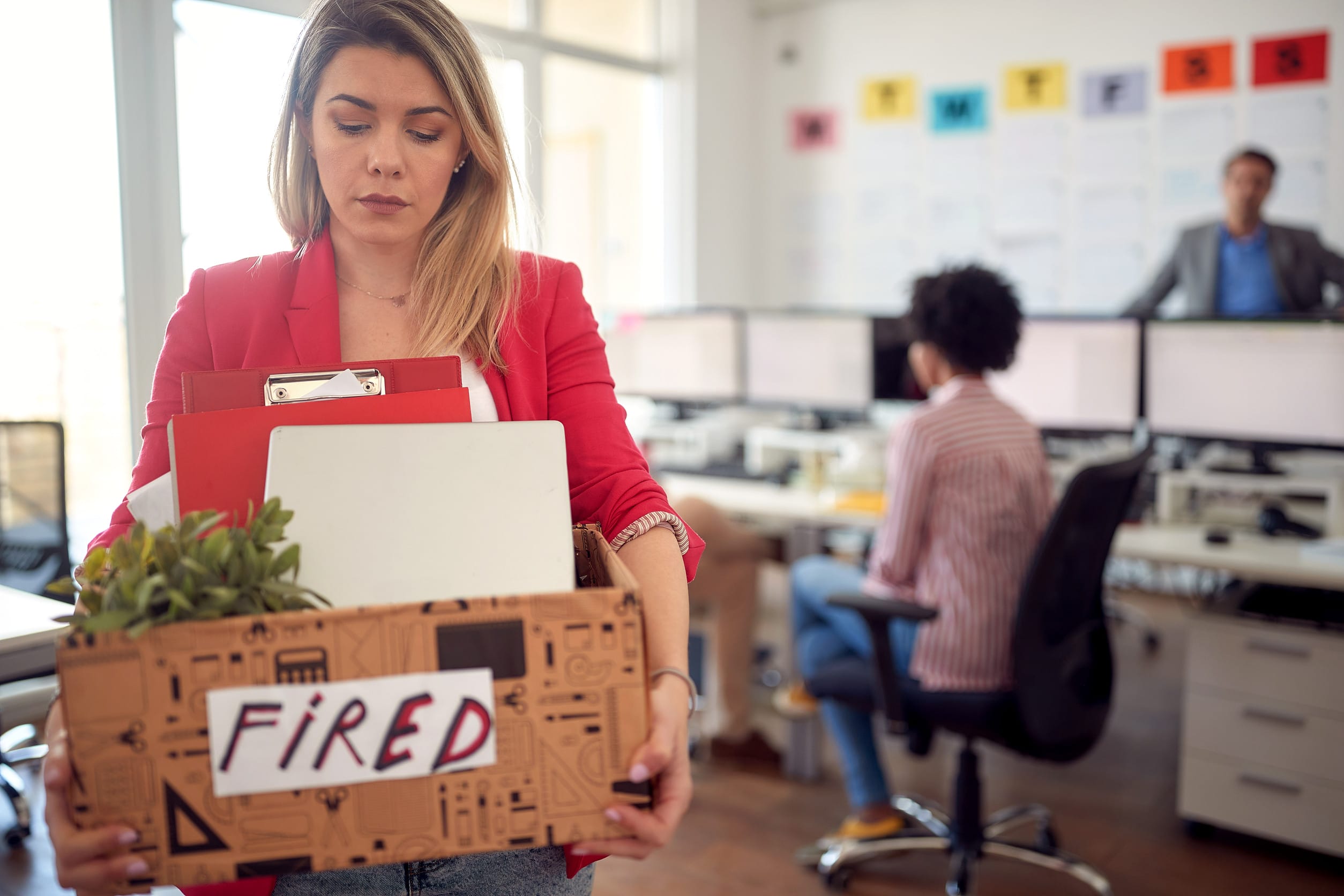 Close-up of a young female holding a box with her belongings and leaving the office after being fired from the job she likes. Employees, job, office