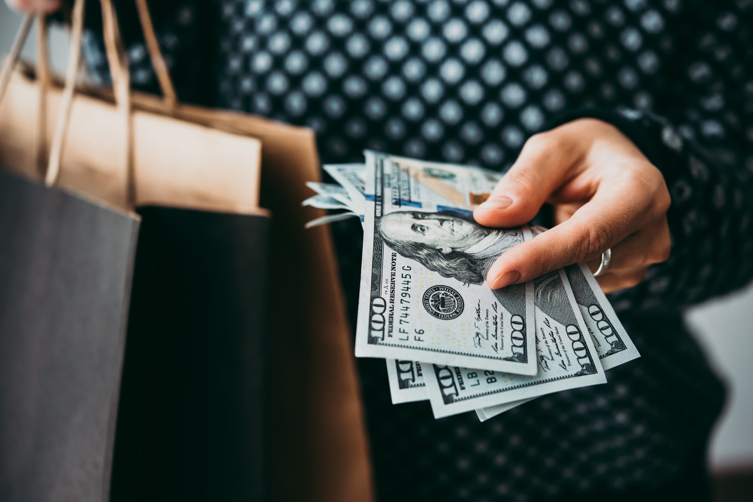 Hands holding dollar bills and paper bags. Shopping concept