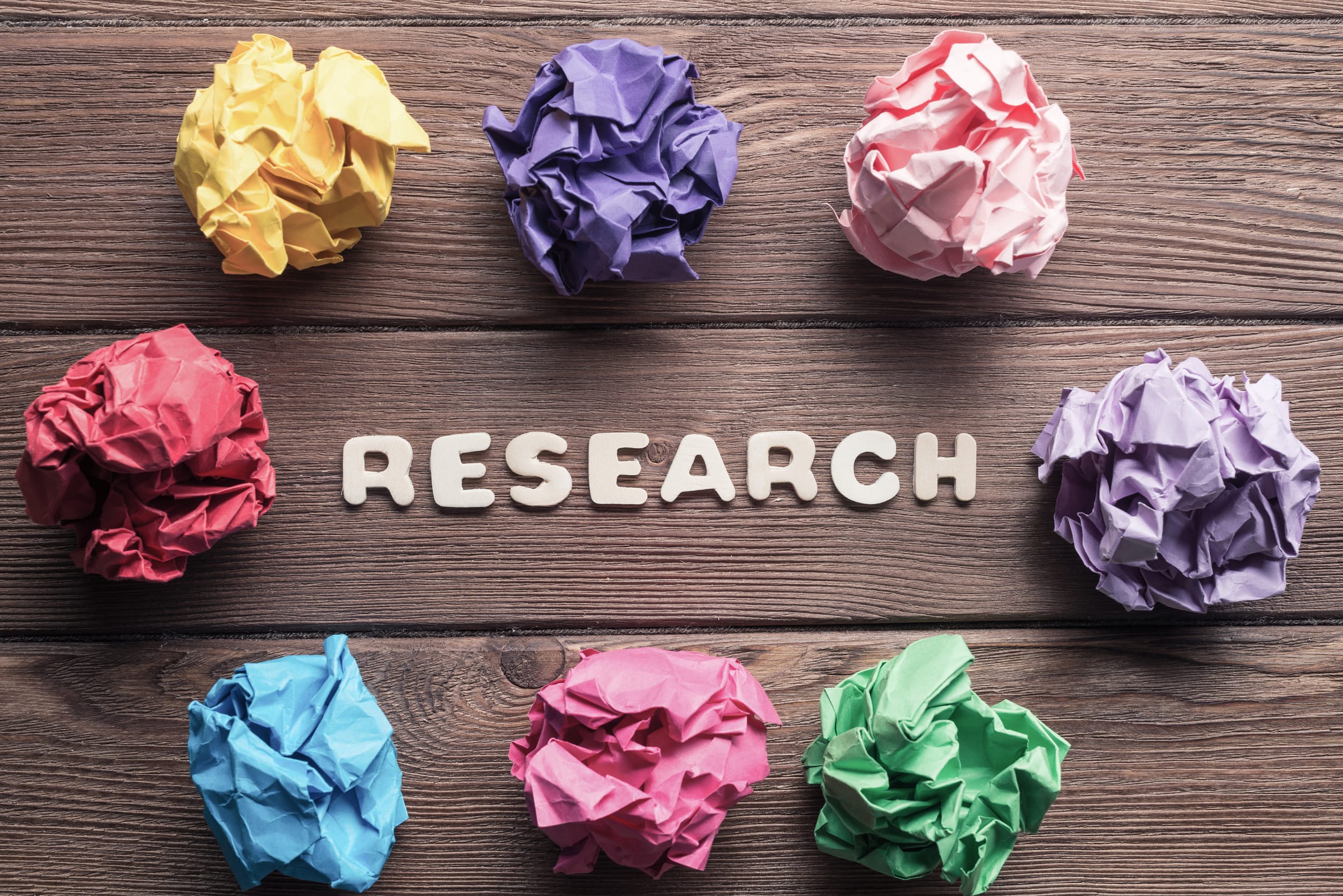 Set of multiple colorful crampled paper ball placed in circle on wooden table