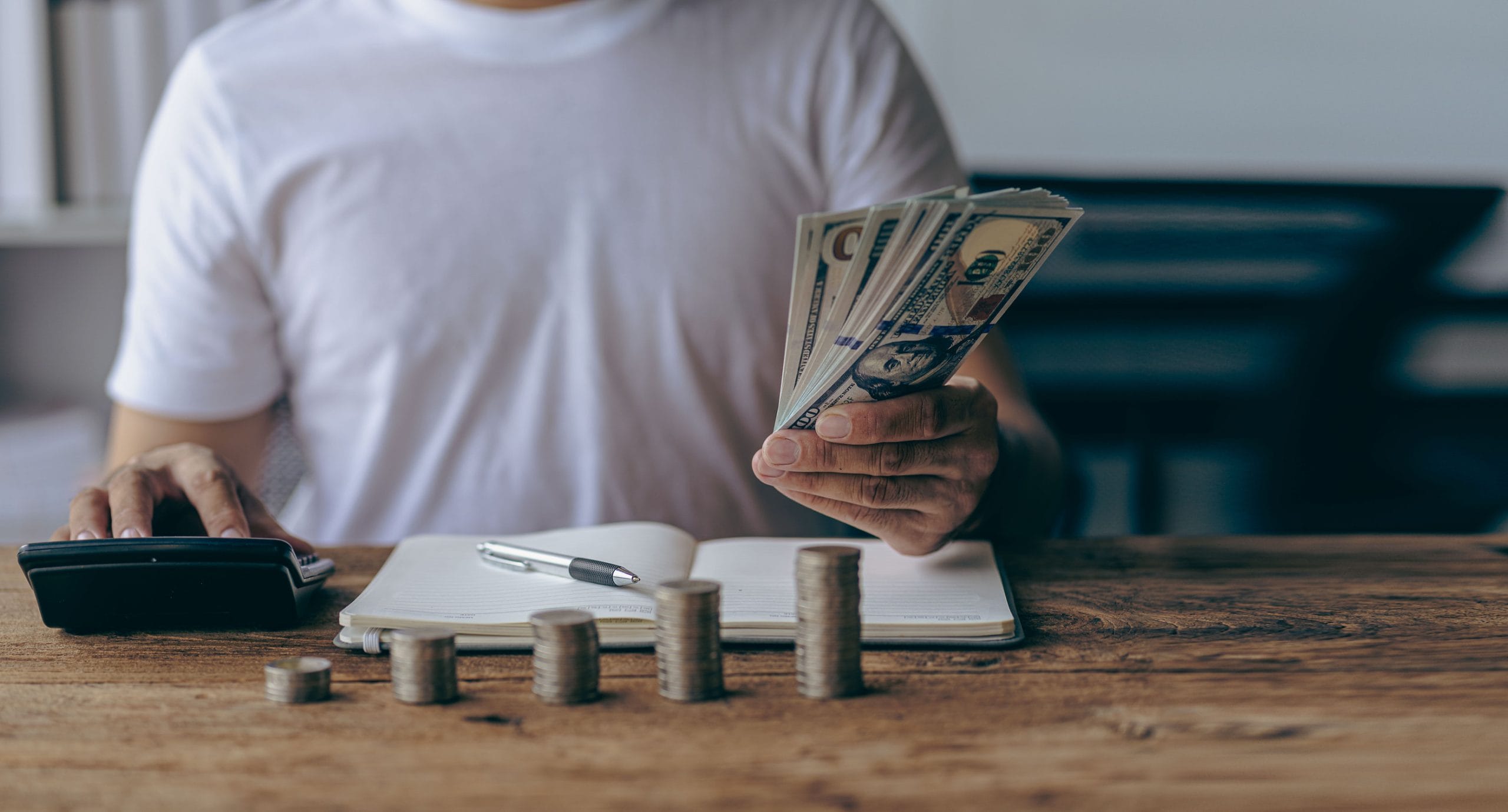 Asian man calculating finances about future expenses or investments at home While the coins are arranged like a graph ahead of the concept of Savings and accounts