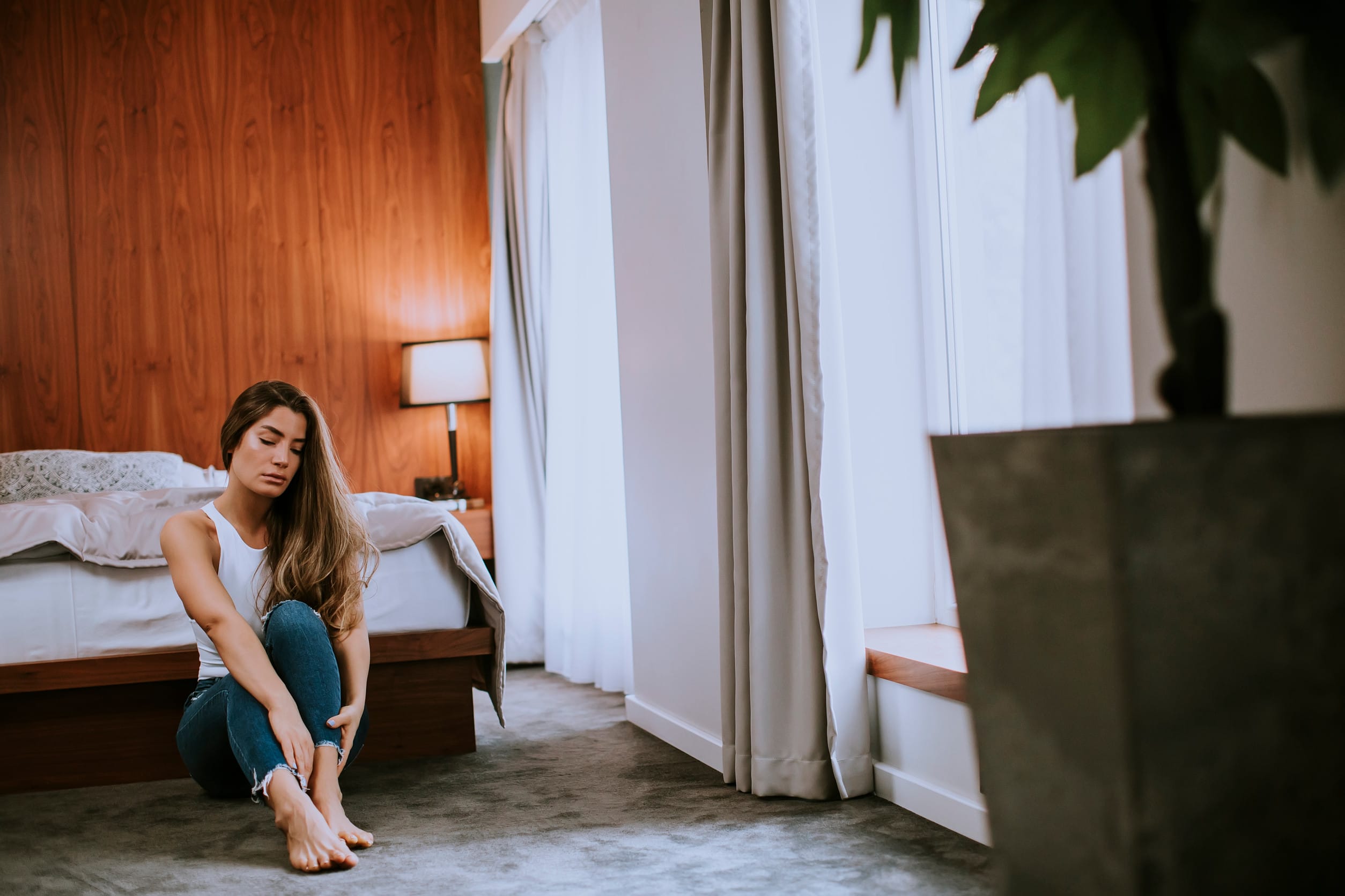 Attractive young woman sitting on the floor in the bedroom at the apartment