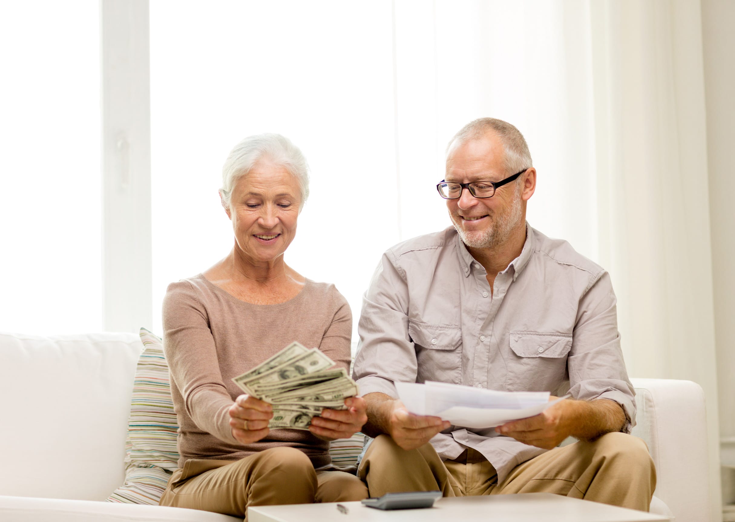 family, business, savings, age and people concept - smiling senior couple with papers, money and calculator at home