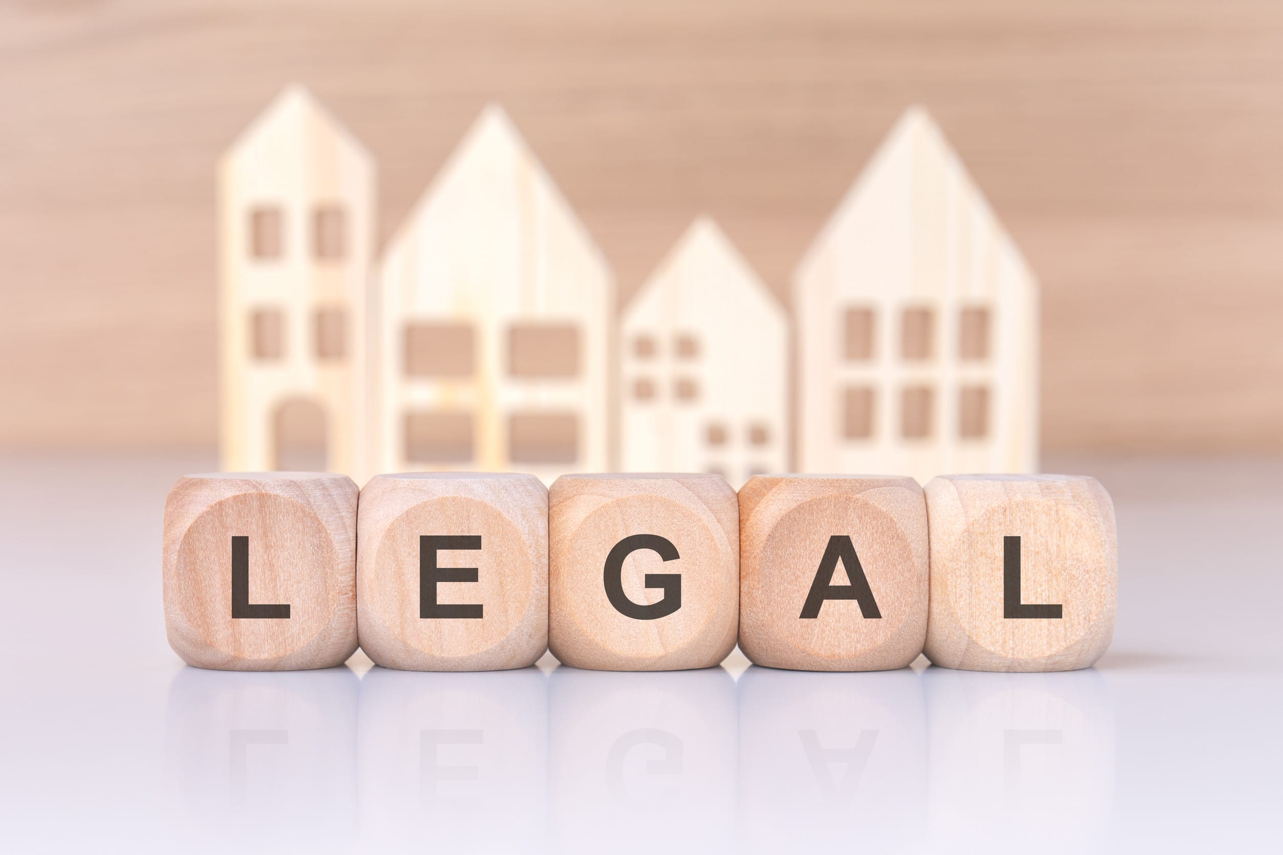 Wooden blocks spelling 'LEGAL' with house cutouts, representing the intersection of law and real estate. This image signifies legal considerations in property transactions, real estate law