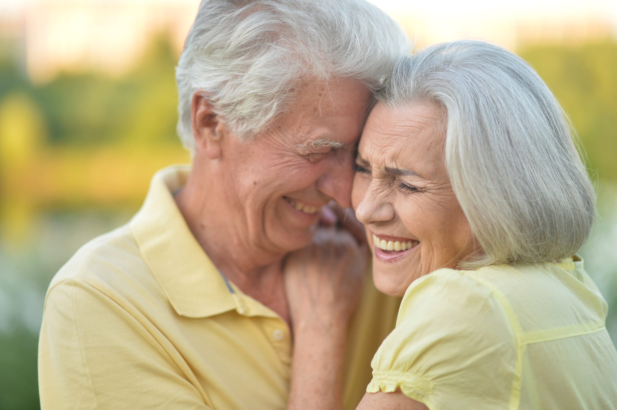 happy senior couple smiling and hugging outdoors