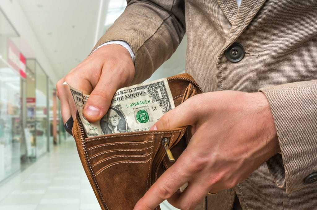 Man holding leather wallet with only one dollar inside